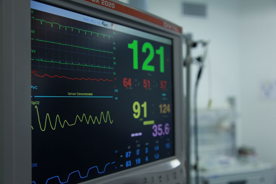 Hospital monitor displaying patient vitals and waveforms; large green 121 bpm and yellow 91 with 'Sensor Disconnected' text visible on screen